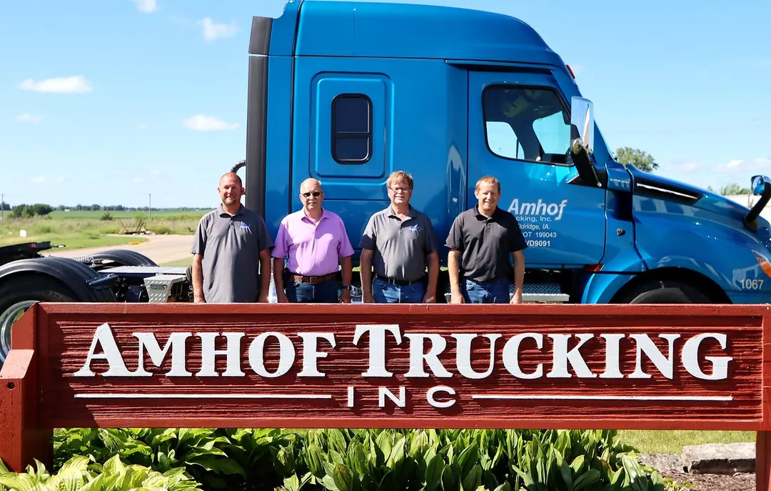 Amhof Trucking team members at the company sign in Eldridge, Iowa